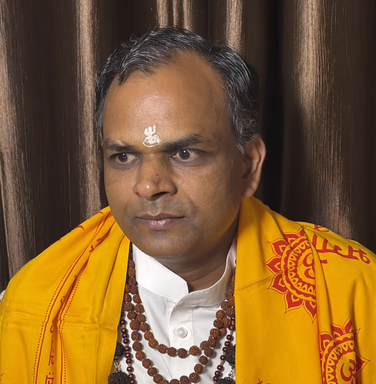 Guruji Mukesh Gupta in traditional Vedic attire with Om symbol.